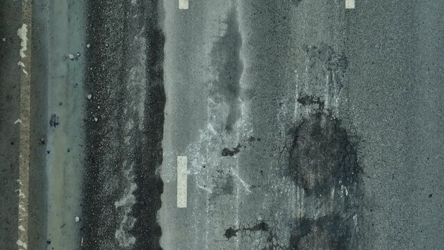 A top-down shot captures an road with visible cracks, spotlighting public works challenges, safety threats, resource allocation, aging infrastructure, environmental consequences, and overdue repairs.
