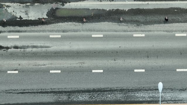 Drone imagery shows an asphalt road in disrepair, symbolizing infrastructure neglect, risk to motorists, lack of resources, city management flaws, environmental exposure, and the call for action.
