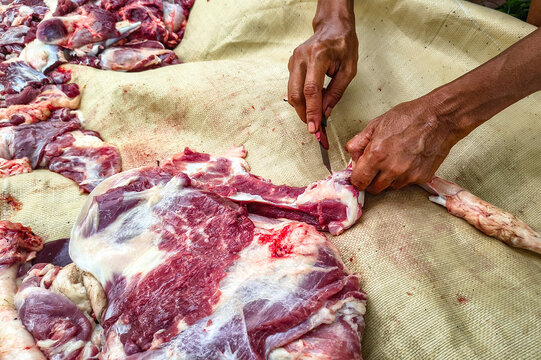 Butcher hands cutting fresh raw meat with knife during Eid al-Adha.
