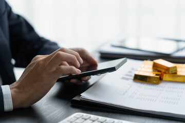 Fototapeta premium Asian businessman using smartphone trading gold bar on online market