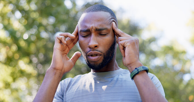 Fitness, runner and black man with headache in nature for pressure, strain and brain fog for health. Sports, exercise and person with head pain for challenge, active hobby and training outdoor