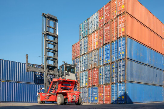 Container Stacking: A robust forklift mechanism stacks colorful shipping containers in a logistics hub, symbolizing global trade and efficient cargo movement under a clear blue sky.