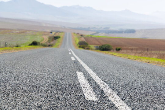 Endless road to horizon through fields and mountains