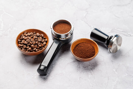 Coffee beans and espresso tools on white marble background