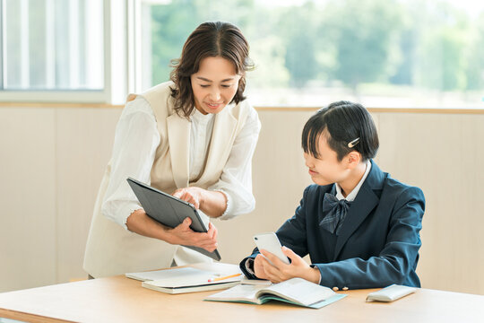 A female student in a school uniform studying at a cram school or preparatory school, and a female instructor teaching her.