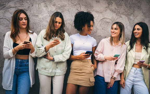 Diverse group of women interacting with smartphones outdoors