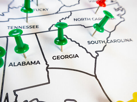Macro close-up of a southern US regional map focusing on Georgia, Alabama, and South Carolina with vibrant green push pins. Perfect for regional logistics, business tracking, and target marketing.