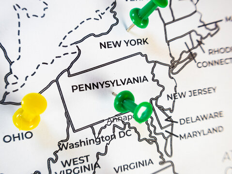 Macro close-up of a US Mid-Atlantic map focusing on Pennsylvania with green and yellow push pins. Ideal concept for regional business logistics, demographic tracking, and corporate expansion.
