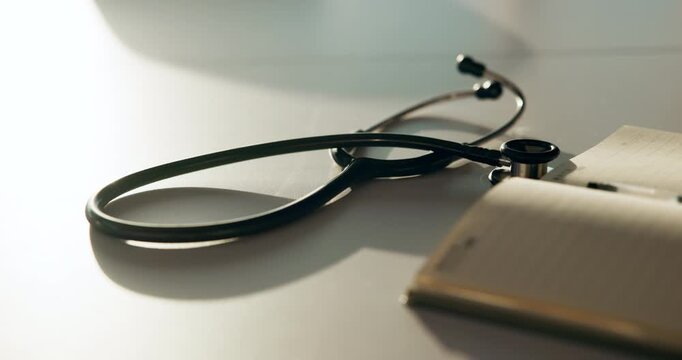 Healthcare, notebook and stethoscope on desk in hospital for heart beat monitor, schedule reminder or wellness. Medical report, cardiology or research with doctors equipment in clinic or empty office