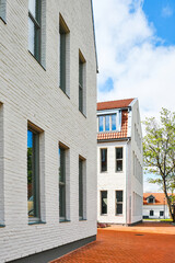 Fototapeta premium Modern white brick apartment buildings with tiled roofs in Europe. Clean minimalist architecture on sunny day.