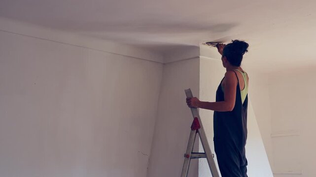 Preparing a ceiling during a DIY home renovation, with a woman on a ladder
