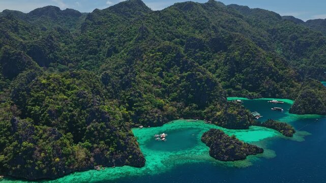Drone descending shot over lush limestone mountains and deep blue ocean channels in Coron, Palawan, Philippines.