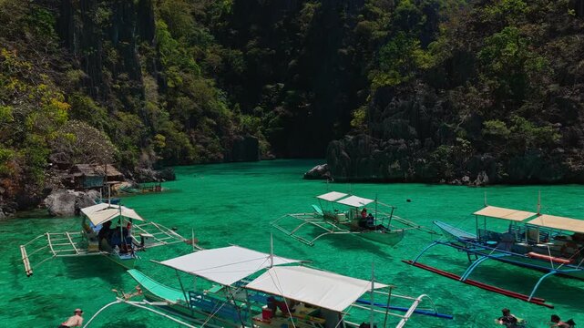 Low aerial forward tracking shot skimming over calm turquoise water inside Twin Lagoon, Coron, Palawan, Philippines.