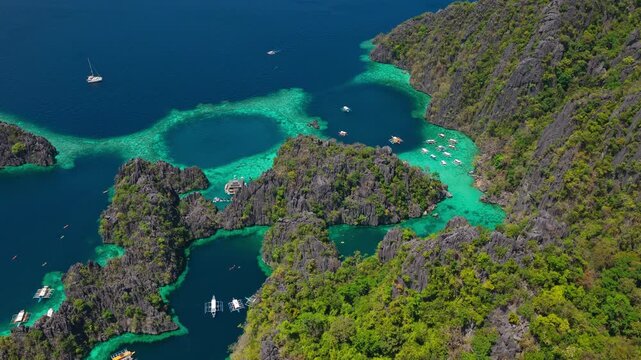Drone orbit shot of traditional outrigger boats anchored in Twin Lagoon, Coron, Palawan, Philippines.