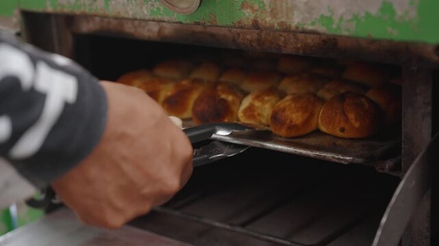 Baker Checking Partially Baked Moringa Pandesal and Returning Bread to Street Oven for Further Baking