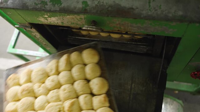 Baker Checking Fresh Moringa Pandesal Before Returning Bread to Oven for Further Baking