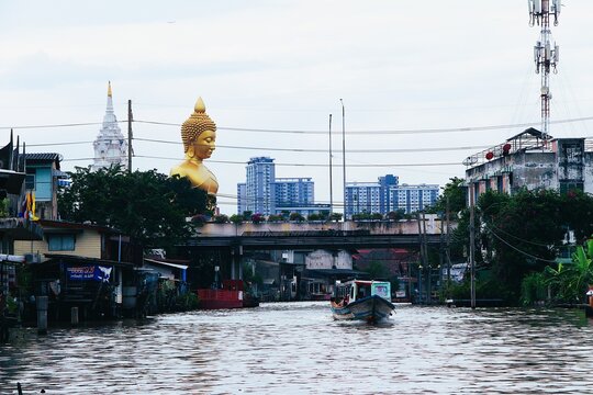 Bangkok Canal View with Tourist Boat and Giant Golden Buddha Statue at Wat Paknam from Phasi Charoen River Thailand