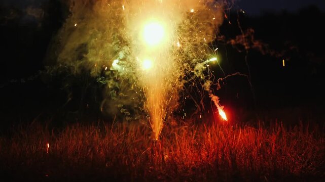Bright festive firework fountain explodes with sparks and smoke at night outdoor celebration.