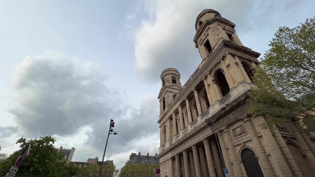Majestic facade of historic Saint-Sulpice church in Paris&rsquo;s Saint-Germain-des-Pr&eacute;s, its iconic stone architecture rising against a dramatic cloudy sky, a beloved city landmark