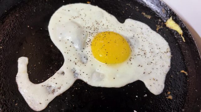 freshly prepared egg fry on hot skillet with golden yolk and white texture