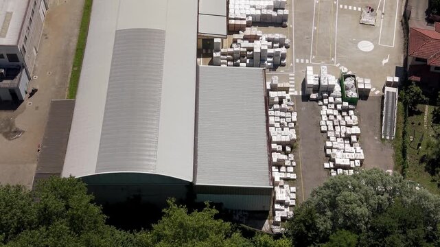 Aerial view of a refractory production plant manufacturing industrial heat-resistant materials. Scene shows heavy industry infrastructure and organized production systems.