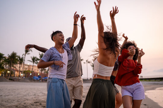 Diverse and multicultural friends dancing on the beach during a summer trip, celebrating friendship