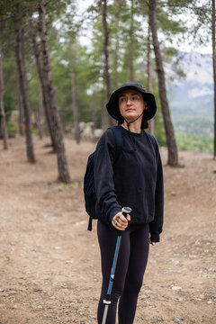 Woman with trekking pole hiking on a forest trail