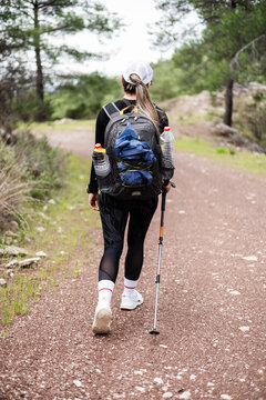 Woman hikes on a gravel path in a forest