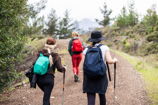 Three women with backpacks hiking on a trail