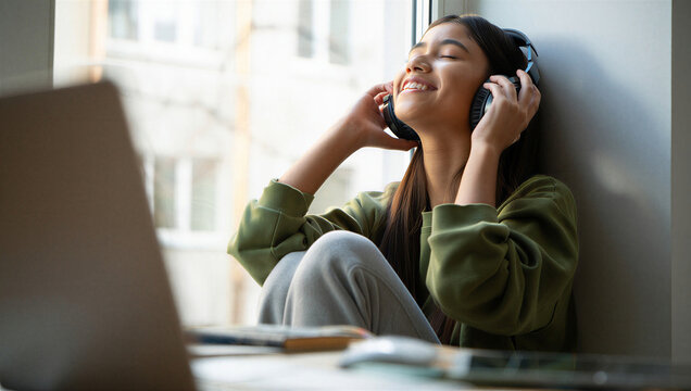Overwhelmed remote student finding instant joyful release by escaping into an uplifting song away from her laptop screen.