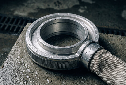 Commercial macro still life. Twin fire hose connection ring (гайка Богданова), milled aluminum, orbital sanding marks. Knurling patterns, Minor dents, translucent water droplets. high-end focus.
