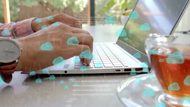 Remote worker typing on keyboard beside teacup, causing turquoise cloud icons and syncing data