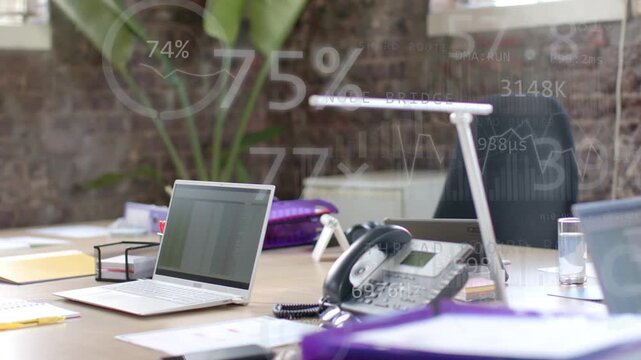Camera panning right changing focus revealing desk cluster laptop phone lamp as graphs showing data