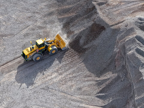 Front loader moving gravel in an industrial mining quarry area