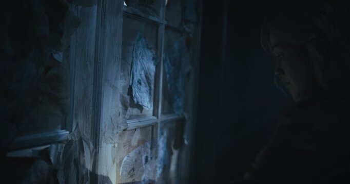 Lone young woman pulling red evidence tape off door and entering spooky, dark room - steady cam shot