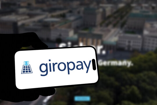 Kiel, Germany - 05-20-2026: Smartphone displaying the German online payment system giropay app in the App Store in a workspace environment with laptop and notebook
