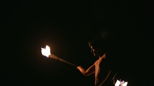 Young man practicing fire twirling performance at night
