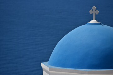 Scenic view of a typical Greek Orthodox church blue dome with a white marble cross against the blue sky in Oia Santorini, Cyclades Greece. © ELENI MAVRANDONI