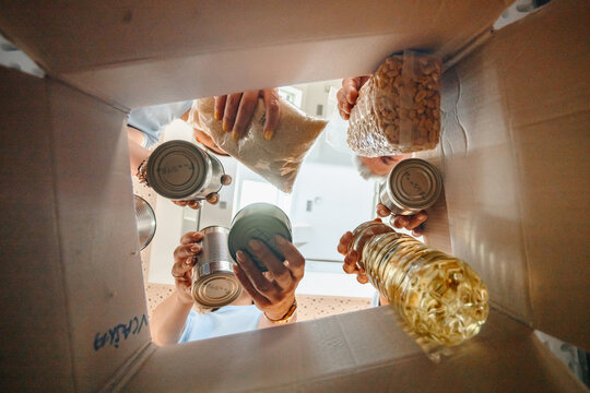 People donating groceries to food bank charity box