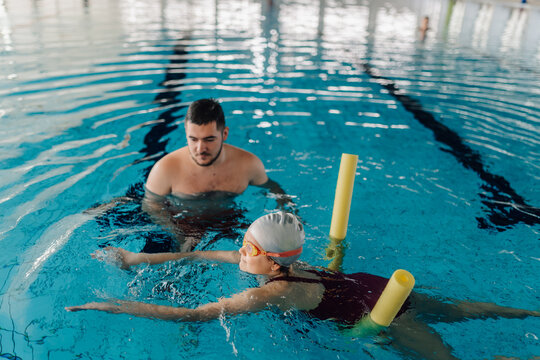 Instructor teaching student swimming strokes in a pool