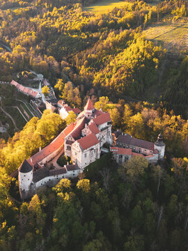 This aerial view shows Pernstejn castle in Czech Republic surrounded by trees. The structure stands strong and historic in a landscape of green hills and trails.