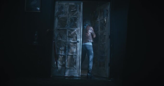 Low, wide, dolly in shot of lone woman with flashlight entering scary, dark room of haunted house