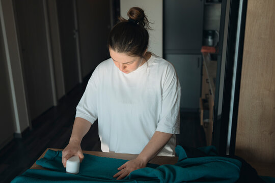 Mid adult woman removing pilling from clothes at home