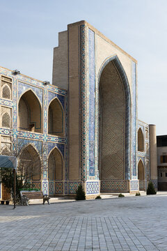 Ulugbek Madrasah facade with ornate blue tilework and pointed arches in Bukhara, Uzbekistan. Historic Islamic architecture ideal for travel publications and cultural heritage content.