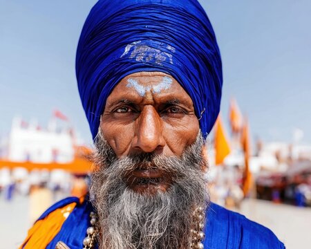 Portrait of a Sikh man in a blue turban looking at camera outdoors for cultural heritage editorial, religious festival coverage and documentary storytelling