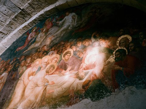 Medieval fresco wall painting depicting a deathbed scene with haloed figures for historical research, religious education and archaeological storytelling documentary