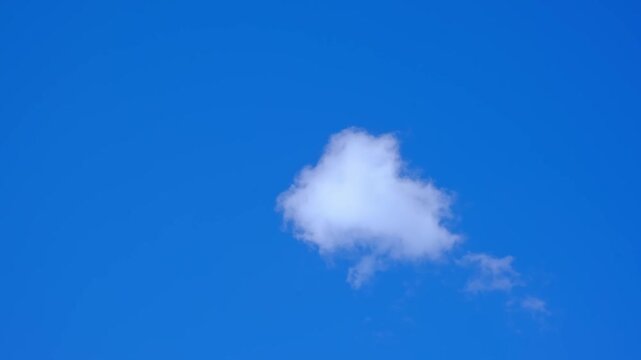 One small white cloud floating in the blue sky at noon. Daylight calm weather afternoon, clear day. Cloudscape or skyscape, nature and freedom concept. Nature environment. Summer colors. Clouds Shape.