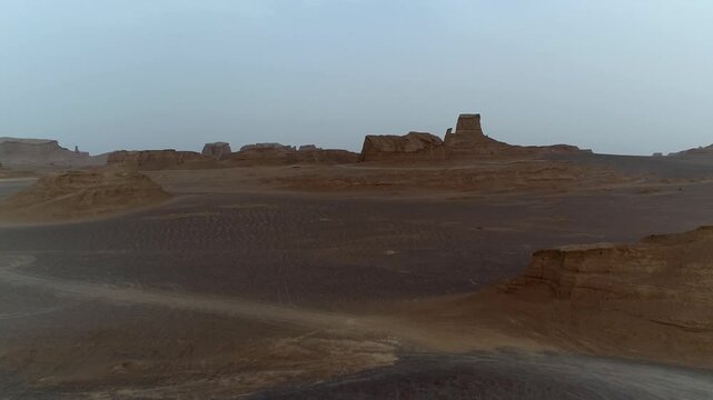 Yardang rock formations line the desert horizon under hazy sky with wind erosion carving dramatic shapes creating epic natural landscape vista perfect for geology and wilderness stock video footage.