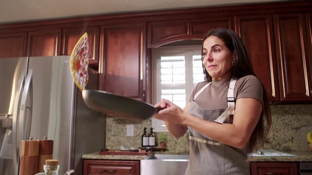 Woman is learning how to cook, tries to flip an omelette but fails.
