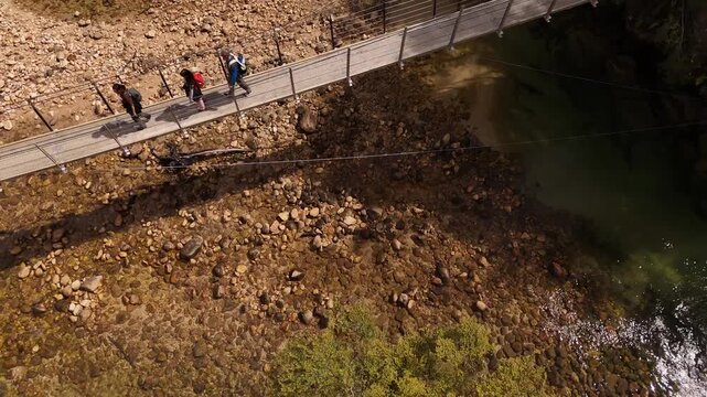 Slow motion shot Of Three People Walking By Suspended Bridge In Abel Tasman Park, South Island, New Zealand